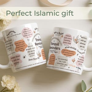 May include: Two white ceramic mugs with inspirational quotes and floral designs. The mugs feature phrases in English and Arabic, with a handle on the side. The mugs are a perfect Islamic gift.