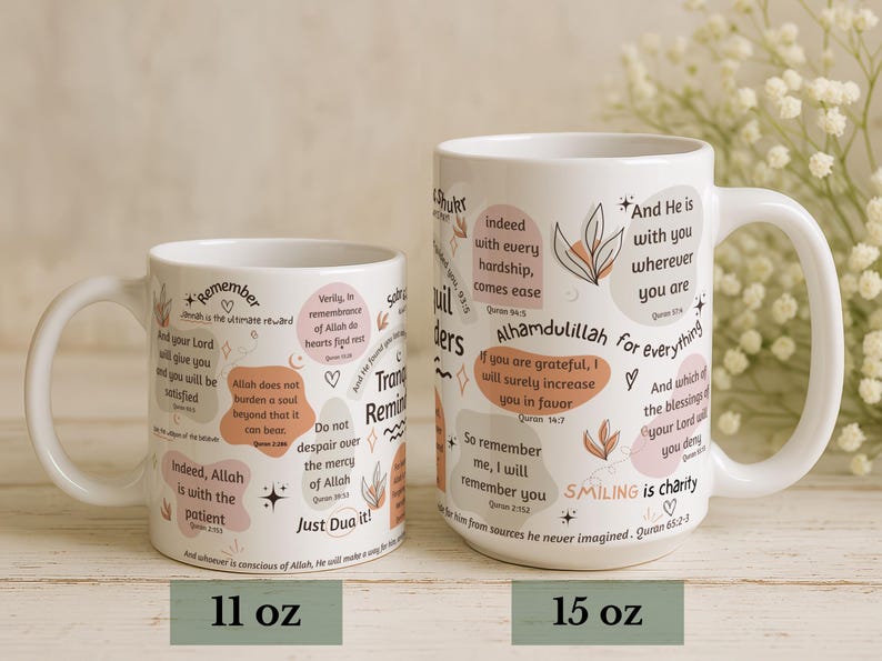 May include: Two white ceramic mugs with inspirational quotes and floral accents. The mugs, labeled 11 oz and 15 oz, feature quotes in English with a light beige and pink color palette. The mugs have a curved handle.