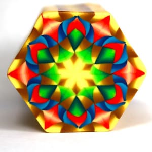 May include: A hexagonal tile with a colorful geometric pattern. The pattern features red, blue, green, and yellow colors arranged in a symmetrical design.