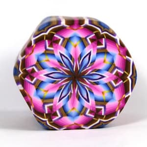 Könnte beinhalten: Ein sechseckiges, mehrfarbiges geometrisches Muster mit rosa, blauen, braunen und goldenen Akzenten. Das Muster erinnert an ein Kaleidoskop.
