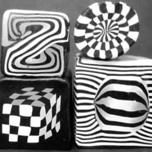 May include: Four black and white geometric patterned clay blocks. The top block has a swirling pattern, the second block has a checkerboard pattern, the third block has a striped pattern, and the bottom block has a striped pattern with a circle in the center.