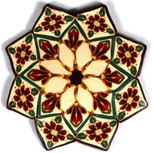 May include: A decorative ceramic plate with a starburst design. The plate is white with red, green, and gold accents. The centre of the plate features a floral pattern.