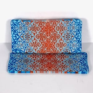 May include: Two rectangular ceramic tiles with a blue and orange geometric pattern. The tiles are stacked on top of each other.