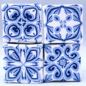 Può includere: Quattro piastrelle quadrate in ceramica con un motivo geometrico blu e bianco. Le piastrelle hanno un design tradizionale con dettagli intricati.