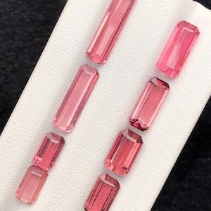 May include: A set of six pink tourmaline gemstones, cut into rectangular shapes, displayed on a white background.
