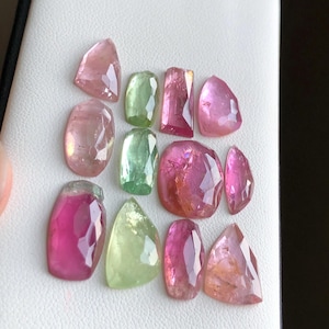 Peut inclure: Une collection de pierres précieuses facettées de différentes formes et tailles. Les gemmes présentent une gamme de couleurs, notamment le rose, le vert et le pêche. Les pierres sont disposées sur une surface blanche, mettant en valeur leur clarté et leur brillance. Idéal pour la joaillerie.