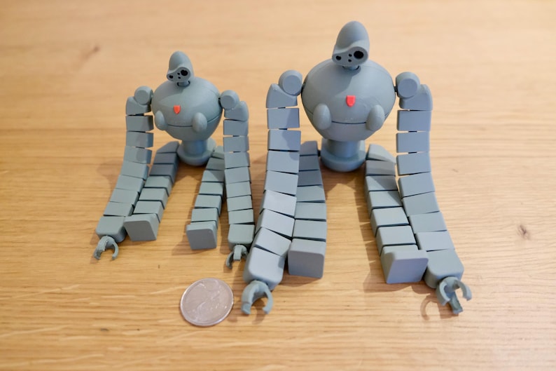 K&ouml;nnte beinhalten: Zwei graue, artikulierte Roboter-Spielzeuge mit segmentierten Gliedma&szlig;en. Der gr&ouml;&szlig;ere Roboter ist etwa doppelt so gro&szlig; wie der kleinere.