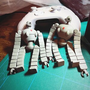 K&ouml;nnte beinhalten: Zwei graue, artikulierte Roboterfiguren mit mehreren segmentierten Gliedma&szlig;en. Die Roboter sind mit erhobenen Armen und gespreizten Beinen posiert. Die Figuren sind aus glattem, mattem Kunststoff.