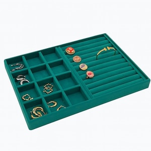 May include: A teal green velvet jewelry tray with various compartments and ring slots. The tray holds an assortment of gold and silver earrings, rings, and a gold bracelet. The jewelry pieces have different designs and colors.