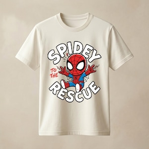 May include: A cream-colored short-sleeve t-shirt featuring a graphic of a cartoon Spider-Man character in a red and blue suit. The text "SPIDEY TO THE RESCUE" is printed in large white letters with a black outline surrounding the character.