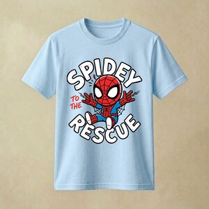 May include: A light blue short-sleeve t-shirt featuring a graphic of a cartoon Spider-Man character in the center. The text "SPIDEY TO THE RESCUE" is printed in white and red around the character, who is shown with web-shooting hands.