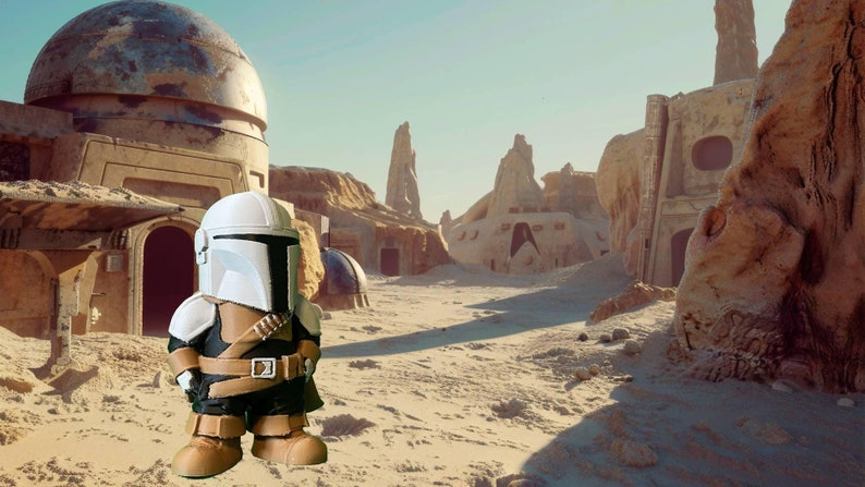 Handcrafted Mandalorian-inspired chibi figure stands in a sandy Tatooine-style desert with dome buildings, perfect for Star Wars fans, gift ideas, or collectors seeking unique handmade decor.