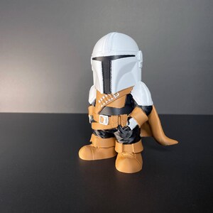 Handmade Mandalorian-inspired chibi figure with a white helmet, golden armor, and cape, standing against a black background—ideal collectible gift for Star Wars fans or geeky decor.