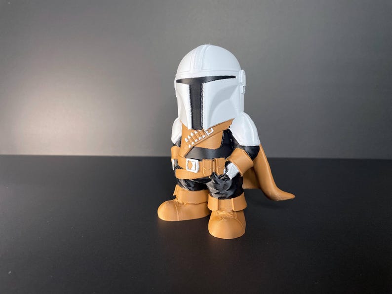 Handmade Mandalorian-inspired chibi figure with a white helmet, golden armor, and cape, standing against a black background—ideal collectible gift for Star Wars fans or geeky decor.