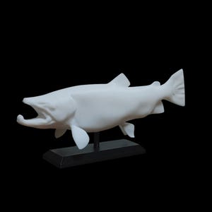 May include: White ceramic sculpture of a salmon fish with its mouth open, mounted on a black base.