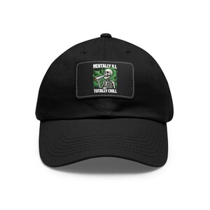 Puede incluir: Gorra de béisbol negra con un parche blanco que muestra un esqueleto de dibujos animados fumando un porro y el texto "Mentally Ill Totally Chill".