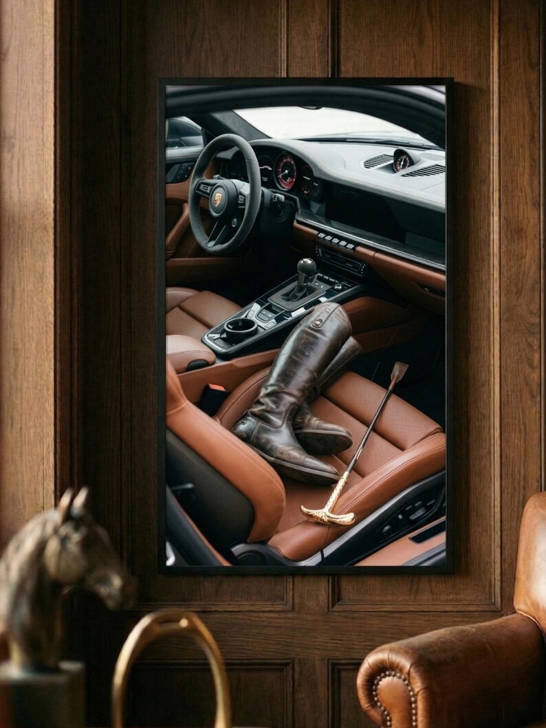 Puede incluir: Imagen enmarcada de un interior de coche de lujo con asientos de cuero marr&oacute;n y un volante. Un par de botas de montar marrones y una fusta con mango dorado descansan en el asiento.