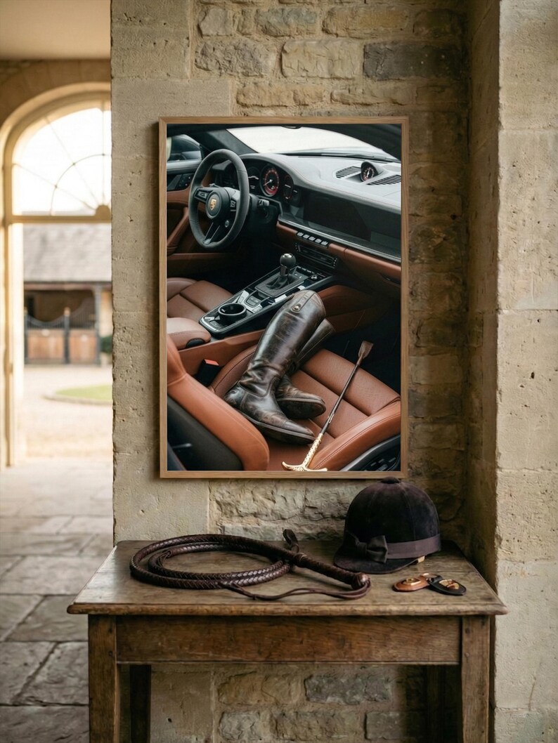Puede incluir: Una fotograf&iacute;a enmarcada de un interior de coche con asientos de cuero marr&oacute;n y botas de montar. Un l&aacute;tigo, un casco de montar y una fusta est&aacute;n sobre una mesa de madera frente a la fotograf&iacute;a.