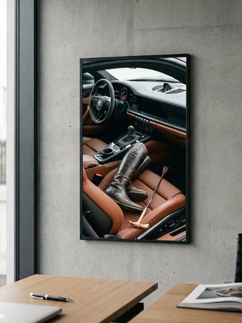 Puede incluir: Imagen enmarcada del interior de un coche con asientos de cuero marr&oacute;n. Un par de botas de montar marrones y una fusta con mango dorado descansan en el asiento. El volante y el salpicadero son visibles.