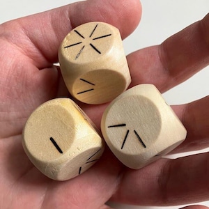 May include: Three wooden dice with black markings. The dice are light brown and have different markings on each side.