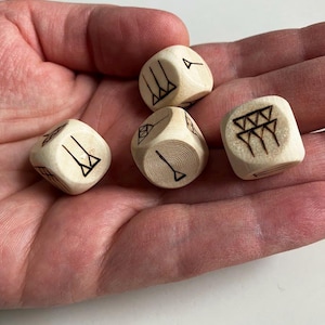 May include: Four wooden dice with different symbols burned into each side. The dice are light brown and have a natural wood finish.