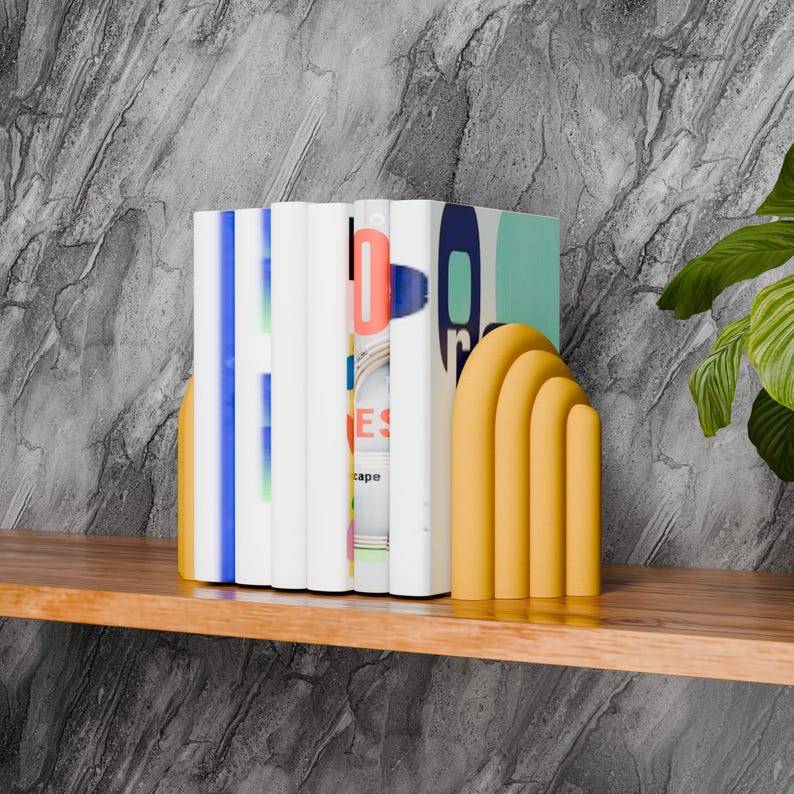 yellow CLOUD bookends holding books on a marble table next to a plant