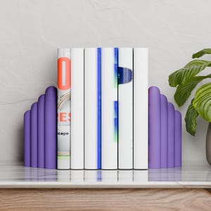 purple CLOUD bookends holding books on a marble table next to a plant