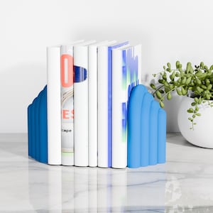 cyan blue CLOUD bookends holding books on a marble table next to a plant