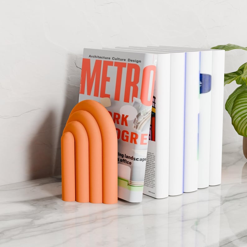 orange CLOUD bookends holding books on a marble table next to a plant