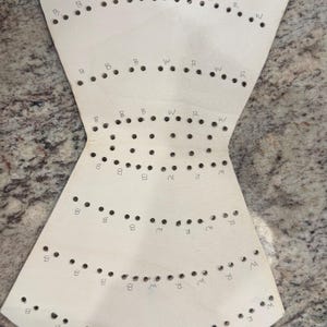 May include: A white paper template with holes and letters marked on it. The letters are "B", "W", and "R".