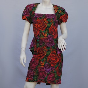 May include: A red, green, and purple floral print dress with a square neckline and puffed sleeves. The dress has a fitted bodice and a full skirt.