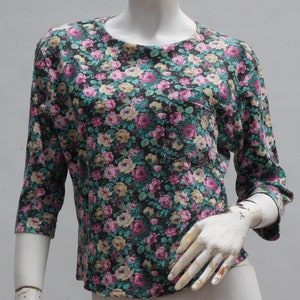 Puede incluir: Una camisa de manga 3/4 de color negro con estampado floral y un peque&ntilde;o bolsillo en el lado izquierdo.