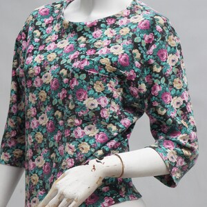 Puede incluir: Una camisa de estampado floral negro con un peque&ntilde;o bolsillo en el lado izquierdo. La camisa tiene cuello redondo y mangas tres cuartos.