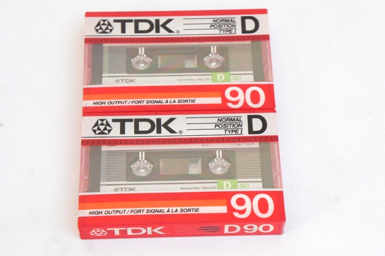 Puede incluir: Tres cintas de casete rojas y plateadas etiquetadas "TDK" con el texto "Posici&oacute;n normal Tipo I" y "D 90" en la parte delantera. Las cintas est&aacute;n etiquetadas "High Output/Fort Signal &agrave; la Sortie" en la parte inferior.