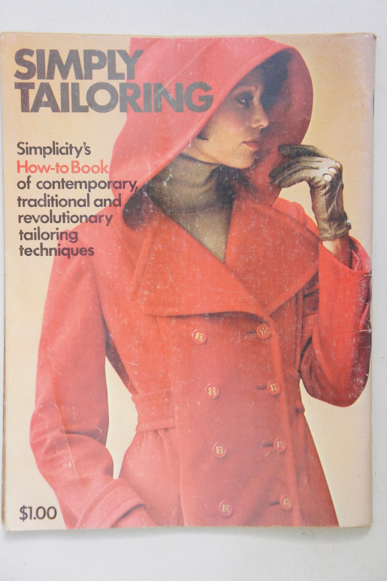 May include: A vintage book titled "Simply Tailoring" with a red cover featuring a woman wearing a red coat with a hood. The book is a Simplicity How-to Book of contemporary, traditional and revolutionary tailoring techniques.