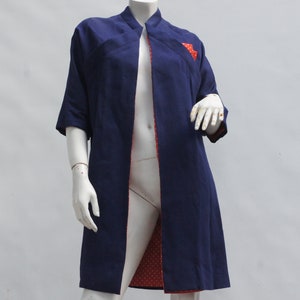 May include: A navy blue long-sleeved jacket with a red and white polka dot lining. The jacket has a mandarin collar and a front opening.