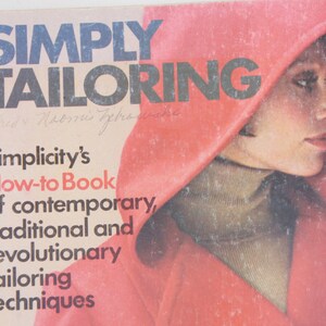 May include: A book cover with the title "SIMPLY TAILORING" in bold black letters. The cover features a woman wearing a red hooded jacket and a turtleneck sweater. The text below the title reads "Simplicity's How-to Book of contemporary, traditional and revolutionary tailoring techniques."