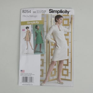 Könnte beinhalten: Simplicity Schnittmuster für ein Vintage-Kleid aus den 1960er Jahren. Das Muster zeigt eine Frau in einem weißen Kleid mit langen Ärmeln und einer kleinen Halskette. Das Muster zeigt auch Illustrationen des Kleides in verschiedenen Farben.