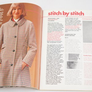 May include: A close-up of a magazine page with a woman wearing a red and white checkered coat. The text on the page reads "stitch by stitch" and discusses traditional and contemporary tailoring methods.