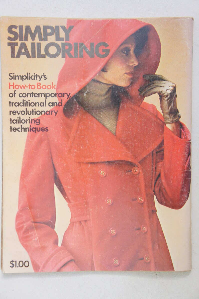 May include: A vintage book titled "Simply Tailoring" with a red cover featuring a woman wearing a red coat with a hood. The book is a Simplicity How-to Book of contemporary, traditional and revolutionary tailoring techniques.