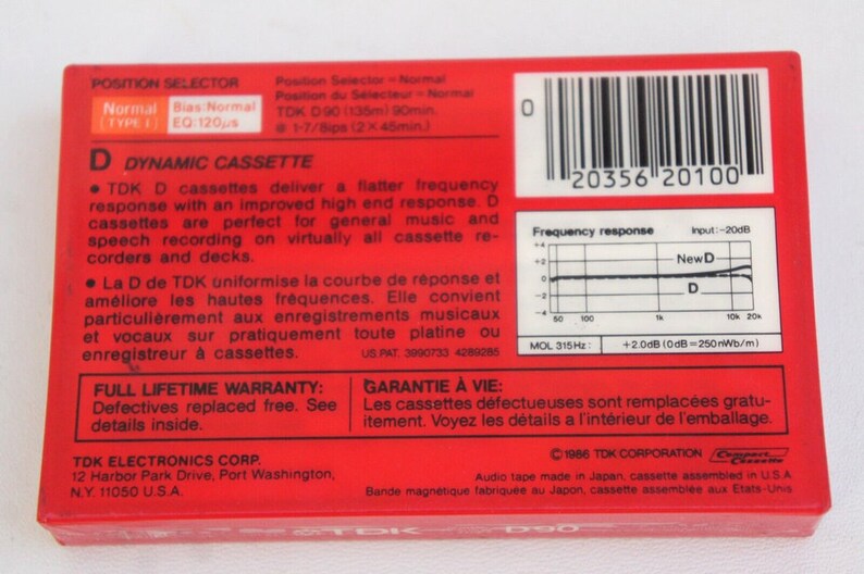 Puede incluir: Caja roja de cinta de cassette con un c&oacute;digo de barras, informaci&oacute;n del producto y un gr&aacute;fico de respuesta de frecuencia. La caja est&aacute; etiquetada como "TDK D90 Cassette Din&aacute;mico" y ofrece una garant&iacute;a de por vida.