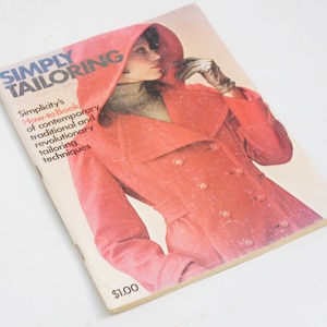 May include: A vintage book titled "Simply Tailoring" with a red cover featuring a woman wearing a red coat with a hood. The book is a how-to guide for contemporary, traditional, and revolutionary tailoring techniques.