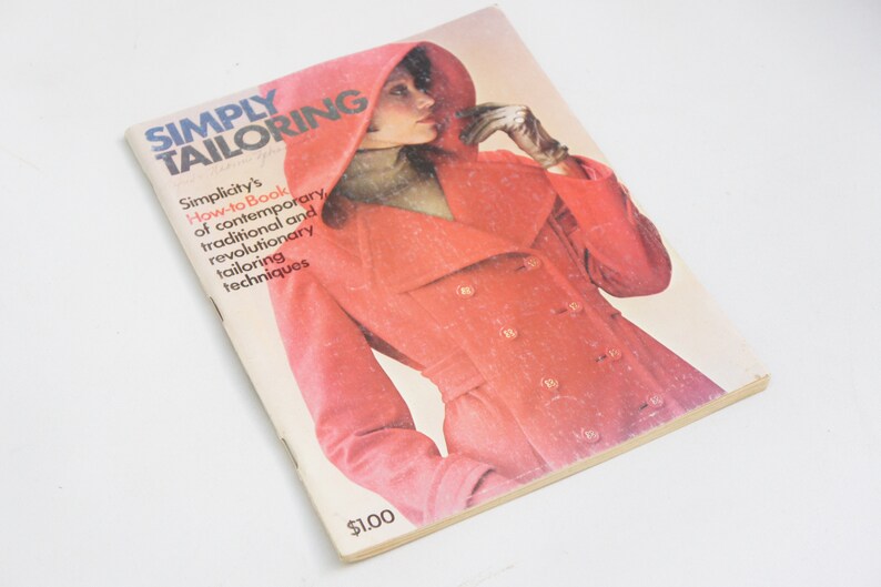 May include: A vintage book titled "Simply Tailoring" with a red cover featuring a woman wearing a red coat with a hood. The book is a how-to guide for contemporary, traditional, and revolutionary tailoring techniques.