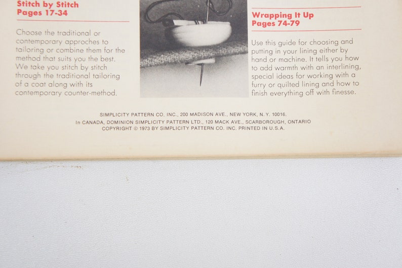 May include: A page from a sewing pattern book with instructions for stitching and wrapping up a coat. The text includes the titles "Stitch by Stitch" and "Wrapping It Up" with corresponding page numbers. The copyright information at the bottom of the page reads "Copyright 1973 by Simplicity Pattern Co. Inc. Printed in U.S.A."