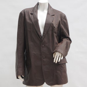 May include: A brown blazer with a two-button closure and two front pockets. The blazer is displayed on a mannequin against a white background. The jacket has a classic lapel and long sleeves.