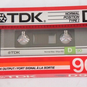 Puede incluir: Una caja de cinta de casete roja, blanca y naranja con el texto "TDK" y "D 90" impreso en ella. La caja est&aacute; etiquetada como "Posici&oacute;n Normal Tipo I" y "Alta Salida/Se&ntilde;al Fuerte a la Salida".