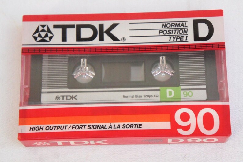 Puede incluir: Una caja de cinta de casete roja, blanca y naranja con el texto "TDK" y "D 90" impreso en ella. La caja est&aacute; etiquetada como "Posici&oacute;n Normal Tipo I" y "Alta Salida/Se&ntilde;al Fuerte a la Salida".