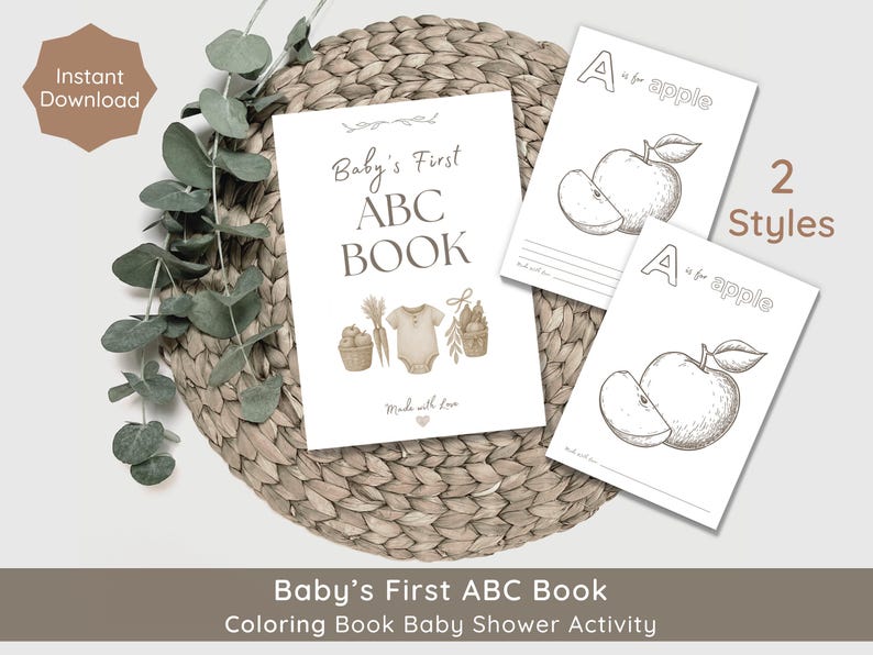 May include: A flat lay of a baby shower activity set. The set includes a "Baby's First ABC Book" and two "A is for apple" coloring pages. The items are arranged on a woven mat with eucalyptus leaves. The words "Instant Download" are visible.