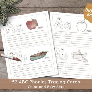 May include: Two educational ABC phonics tracing cards with illustrations of an apple and a boat. The cards feature uppercase and lowercase letters for tracing practice. A marker rests on the cards. The text reads "52 ABC Phonics Tracing Cards - Color and B/W Sets - Biblical Edition."
