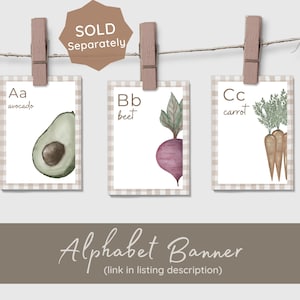 A white ABC book titled 'Logan's First ABC BOOK' with illustrations of a carrot, basket, and baby clothes. The book is displayed with other pages that say 'C is for carrot' and 'E is for eggs'. The image has a light brown background with five white heart outlines.